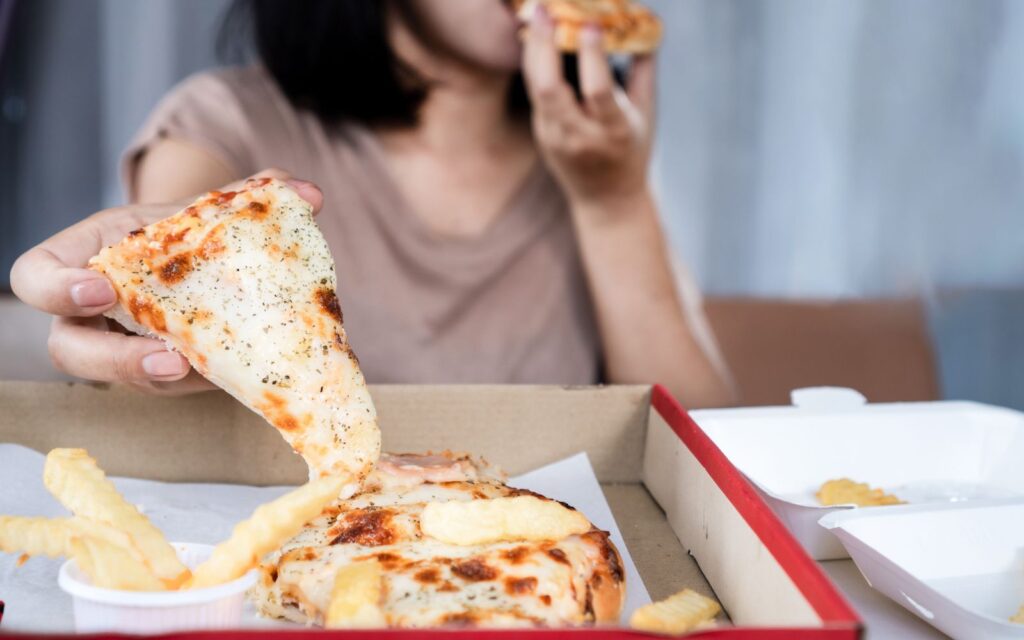 Persona che mangia pizza e cibo da asporto da sola